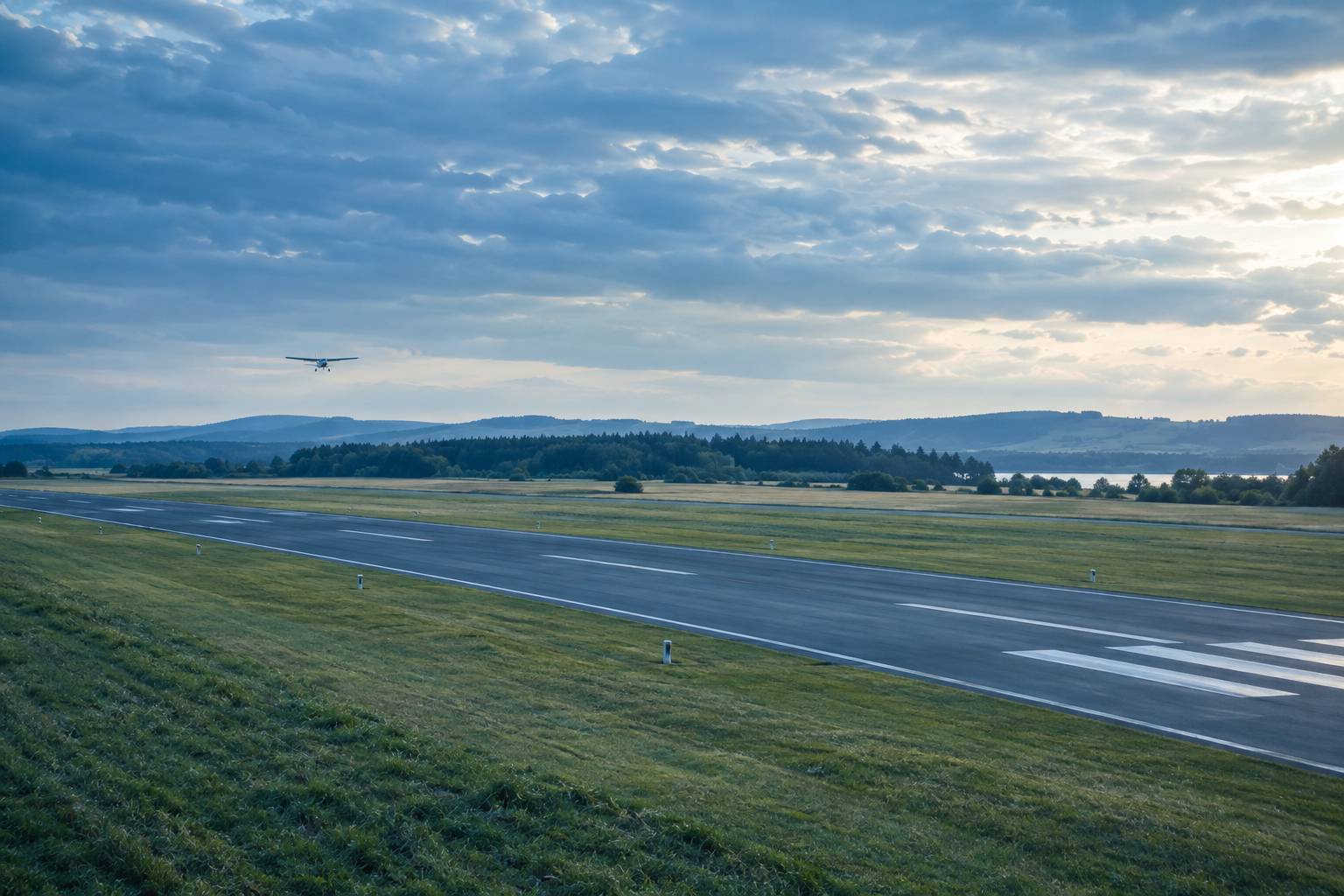 Petit avion léger stationné devant un hangar d'aérodrome civil au matin, sans enseigne ni logo